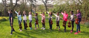 Children posing with violins in garden