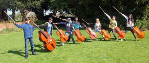 Children posing with large string instruments in garden